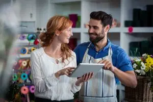 AdobeStock_123673035_EBC Eine Frau und ein Mann stehen in einem Blumen-Geschenkeladen und halten ein Tablet in der Hand.