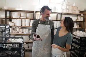 2 Personen in einem Kaffee, die lachend auf ein Tablet schauen