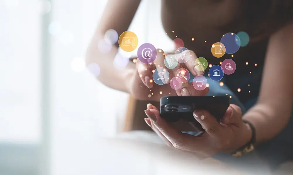 Frau bedient ihr Smartphone. Viele kleine Icons schweben darüber. Beispiel für mobile Apps, die das Einkaufserlebnis beschleunigen.