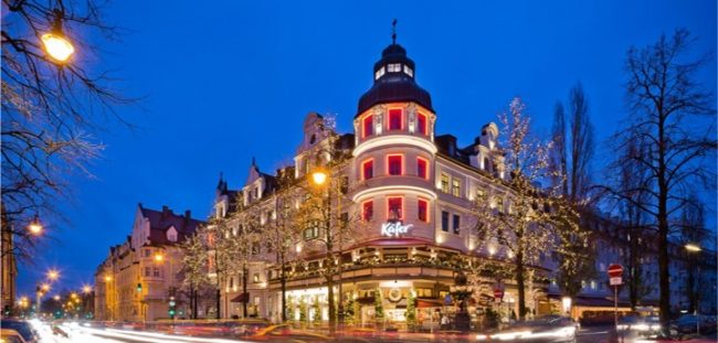 Ansicht des Eingangs vom Hauptgebäude von Käfer Feinkost mit weihnachtlicher Beleuchtung.