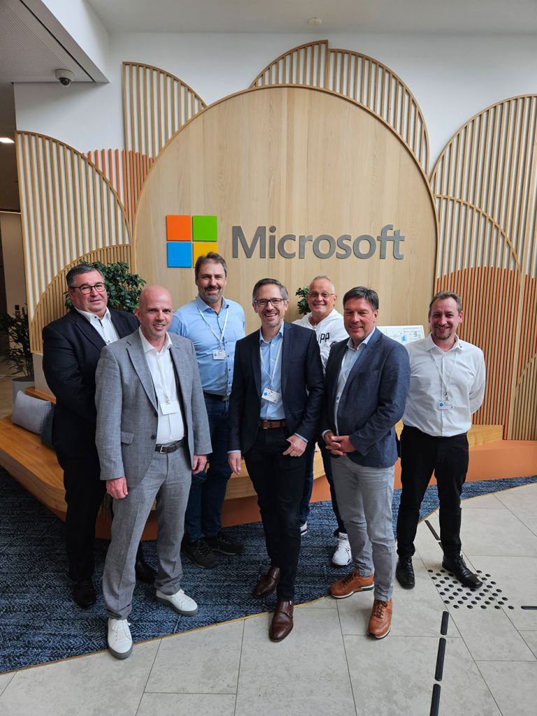 Gruppenfoto aller Referenten vor dem Microsoft-Logo.