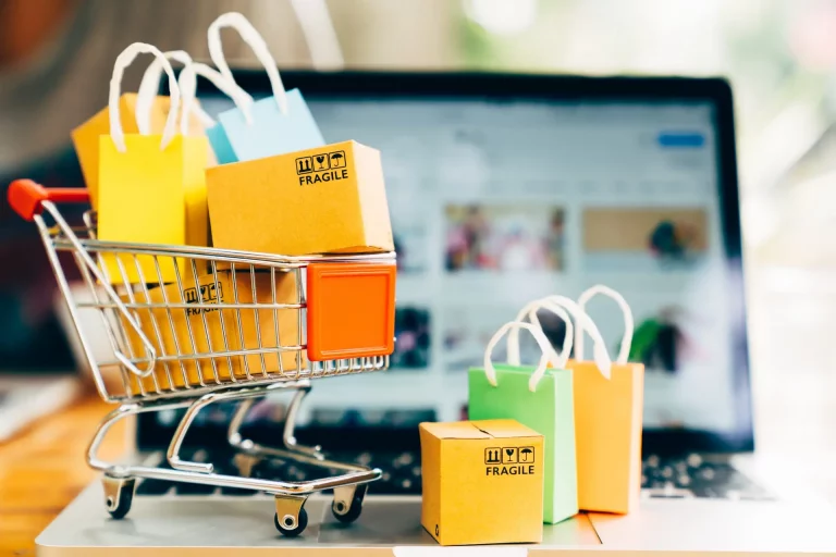 Product package boxes and shopping bag in cart with laptop compu ein kleiner EInkaufswagen vor einem Laptop