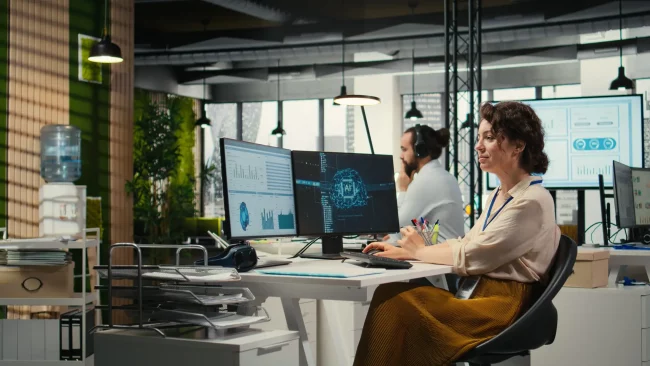 Büroverwalter, der Monatsberichte mithilfe einer KI-Analyseplattform überprüft und dabei Algorithmen auf Basis neuronaler Netze sowie Automatisierungsmaßnahmen zur Effizienzsteigerung einsetzt. Vertreter eines IT-Unternehmens bei der Arbeit.