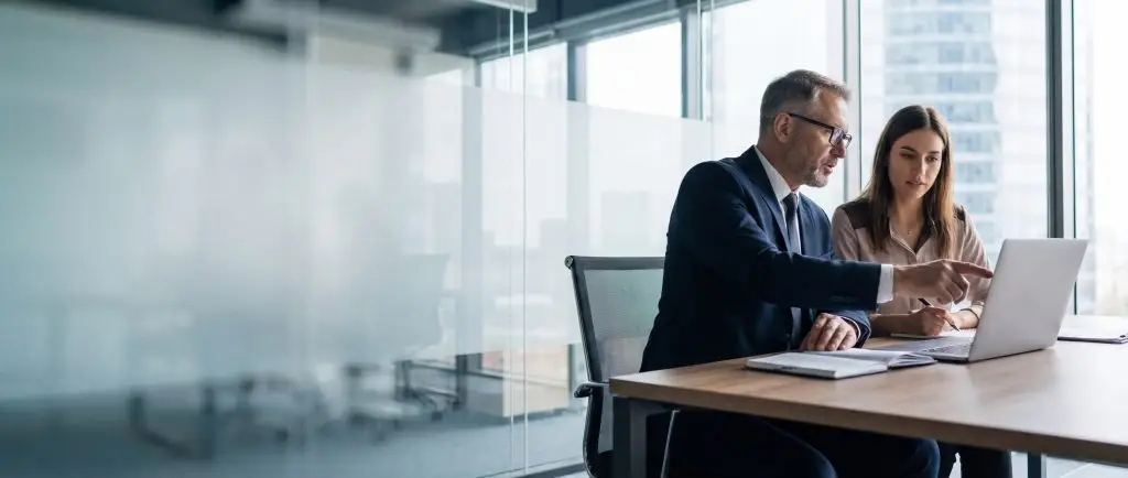 Zwei professionelle Geschäftsleute bei der Zusammenarbeit. Ein reifer Mann und eine reife Frau als Partner besprechen ein Projekt im Büro. Der Teamleiter erklärt einem Auszubildenden mithilfe eines Tablet-PCs den Arbeitsablauf. Banner, Textfeld