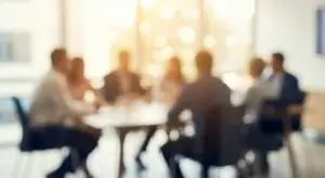 Ein unscharfes Bild einer Geschäftssitzung, bei der mehrere Fachleute an einem Konferenztisch diskutieren und eine Atmosphäre der Zusammenarbeit schaffen.