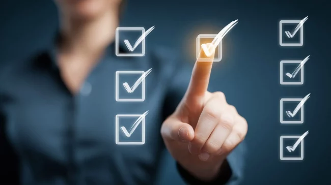 AdobeStock_2113714738 weiße Haken auf einer Glasscheibe. Jemand tippt mit dem Finger auf einen der Haken