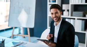 Tablet, lächelndes Gesicht und Porträt eines Geschäftsmannes im Büro für ERP-Statistiken, Diagramme und die Online-Datenanalyse im Rahmen von Forschungsarbeiten. Digitale Technologie, Gesicht und fröhlicher Finanzberater bei der Planung eines Projekts in Saudi-Arabien.